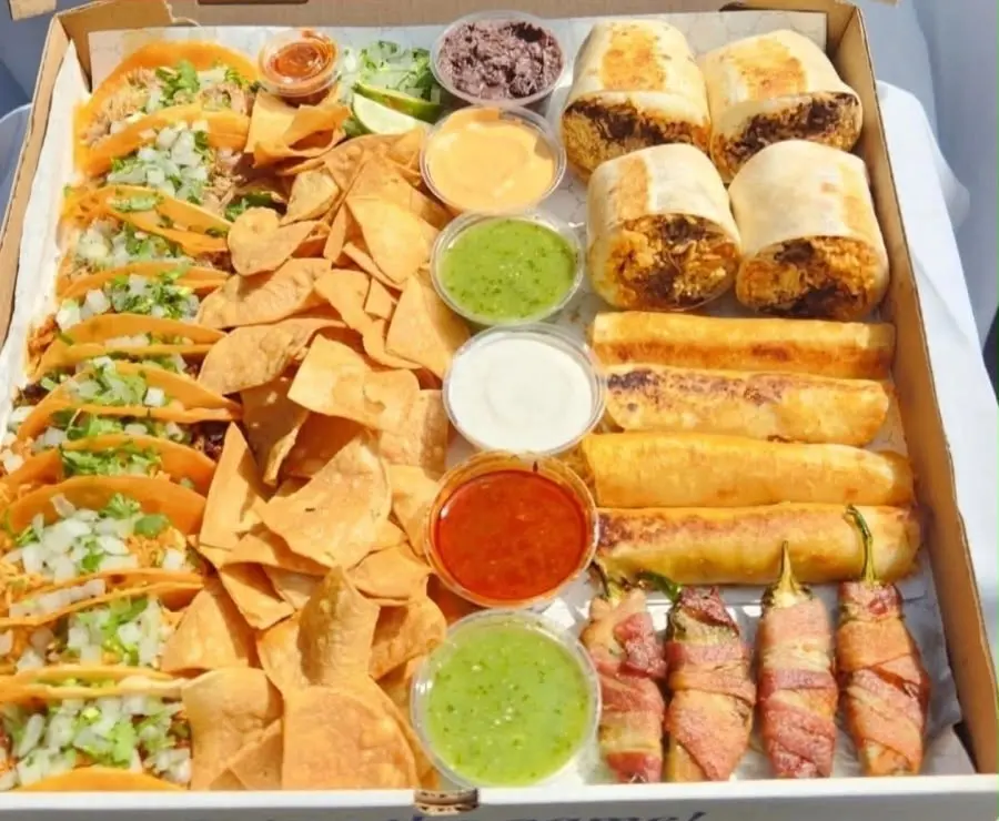 A party box of tacos, burritos, taquitos, bacon-wrapped jalapeños, chips and salsas