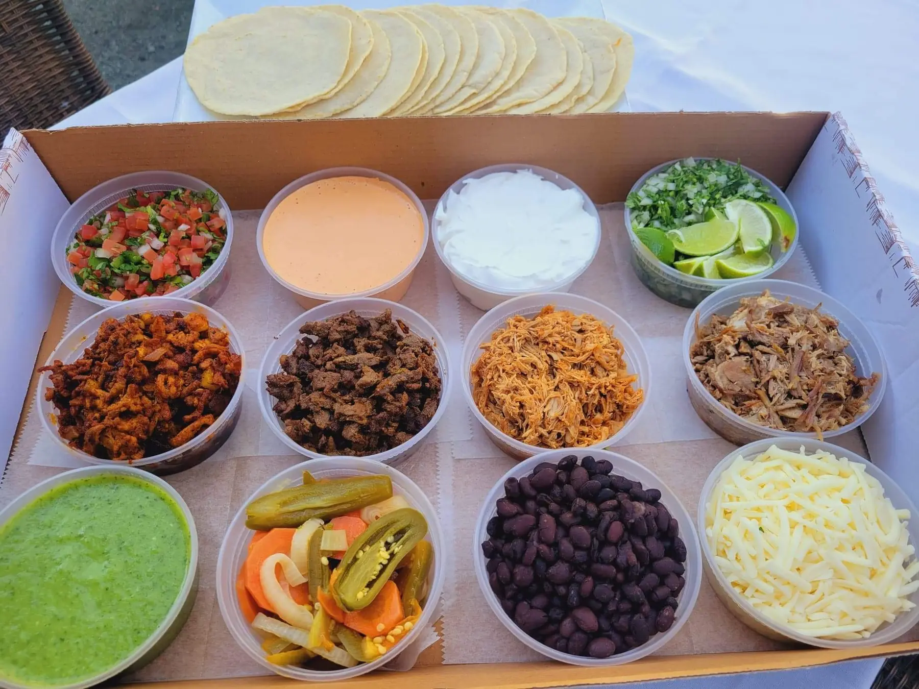 A nacho bar of chips, queso, beans and salsas in catering trays