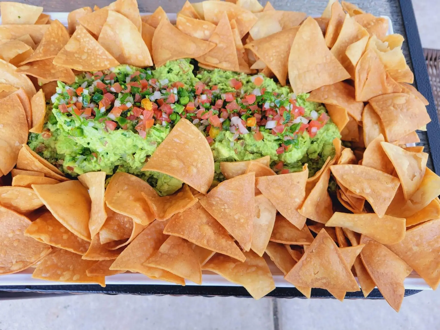 Tortilla chips piled with guacamole and pico de gallo