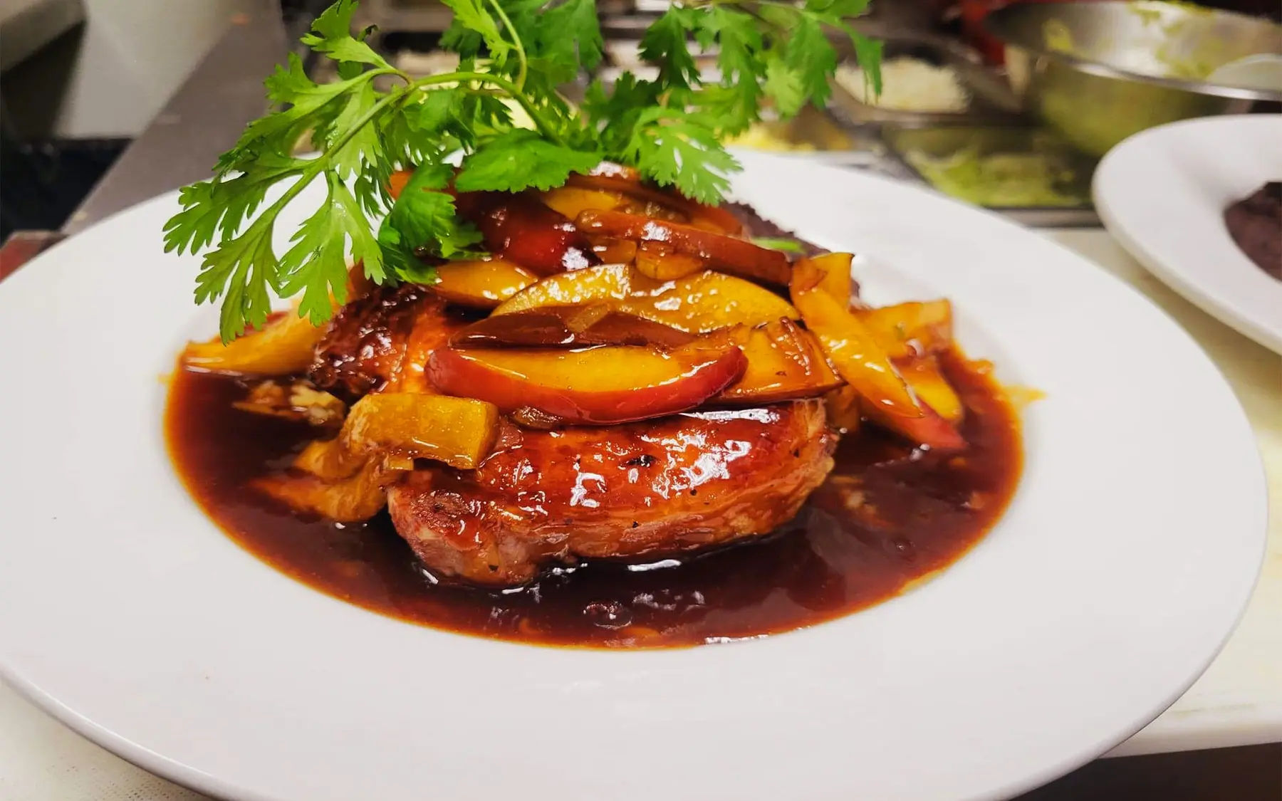 Pork chop topped with honey-crisp apples in a glossy chipotle demi-glace