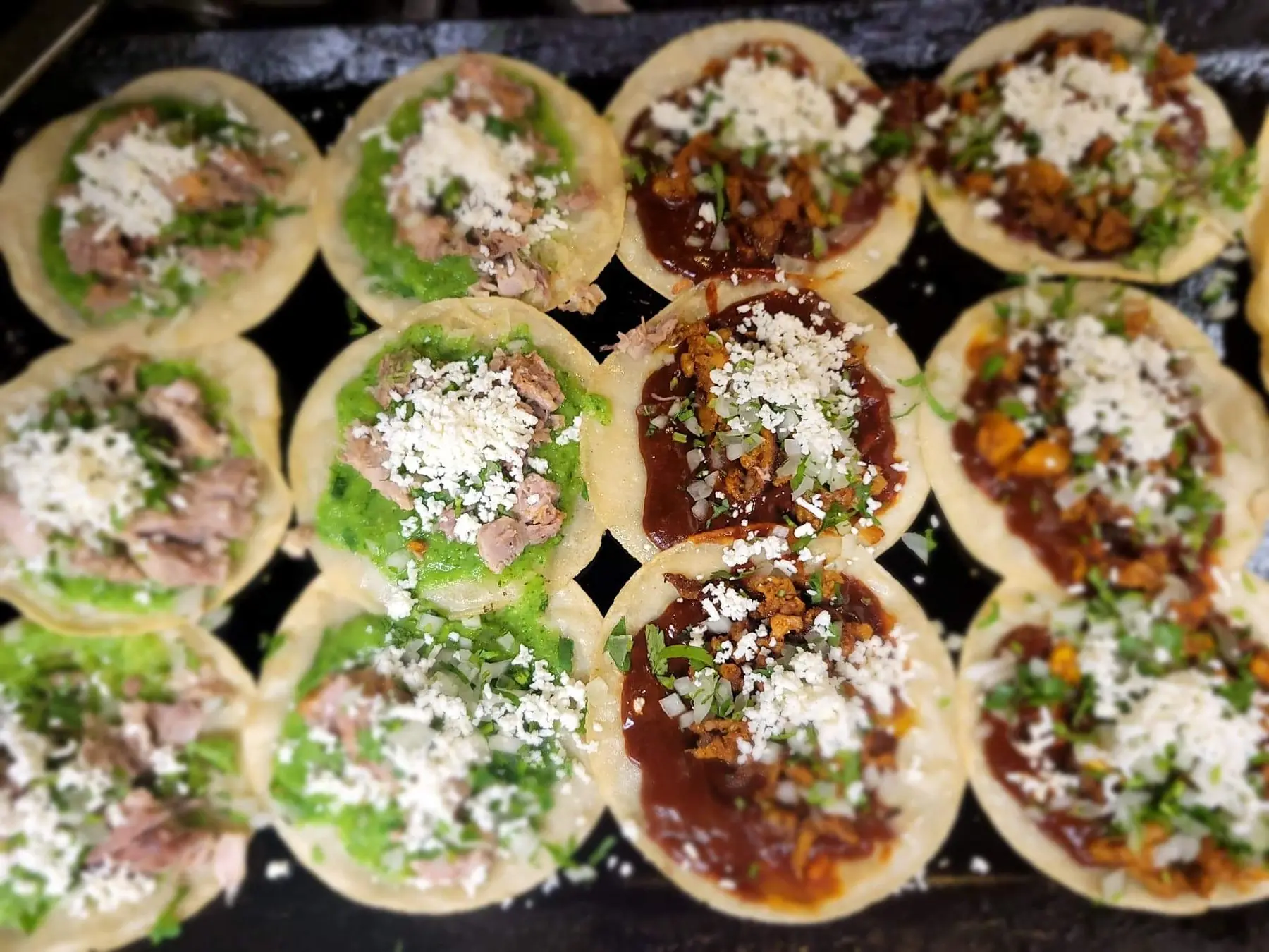 Small corn tortilla tacos topped with salsa and queso fresco