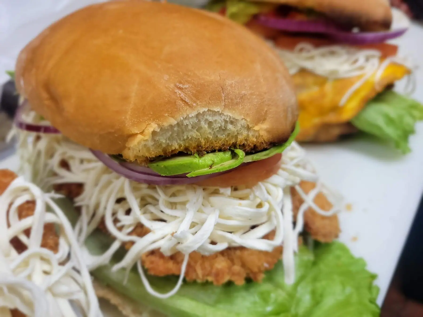 A torta stacked with breaded chicken, Oaxaca cheese, avocado and red onion