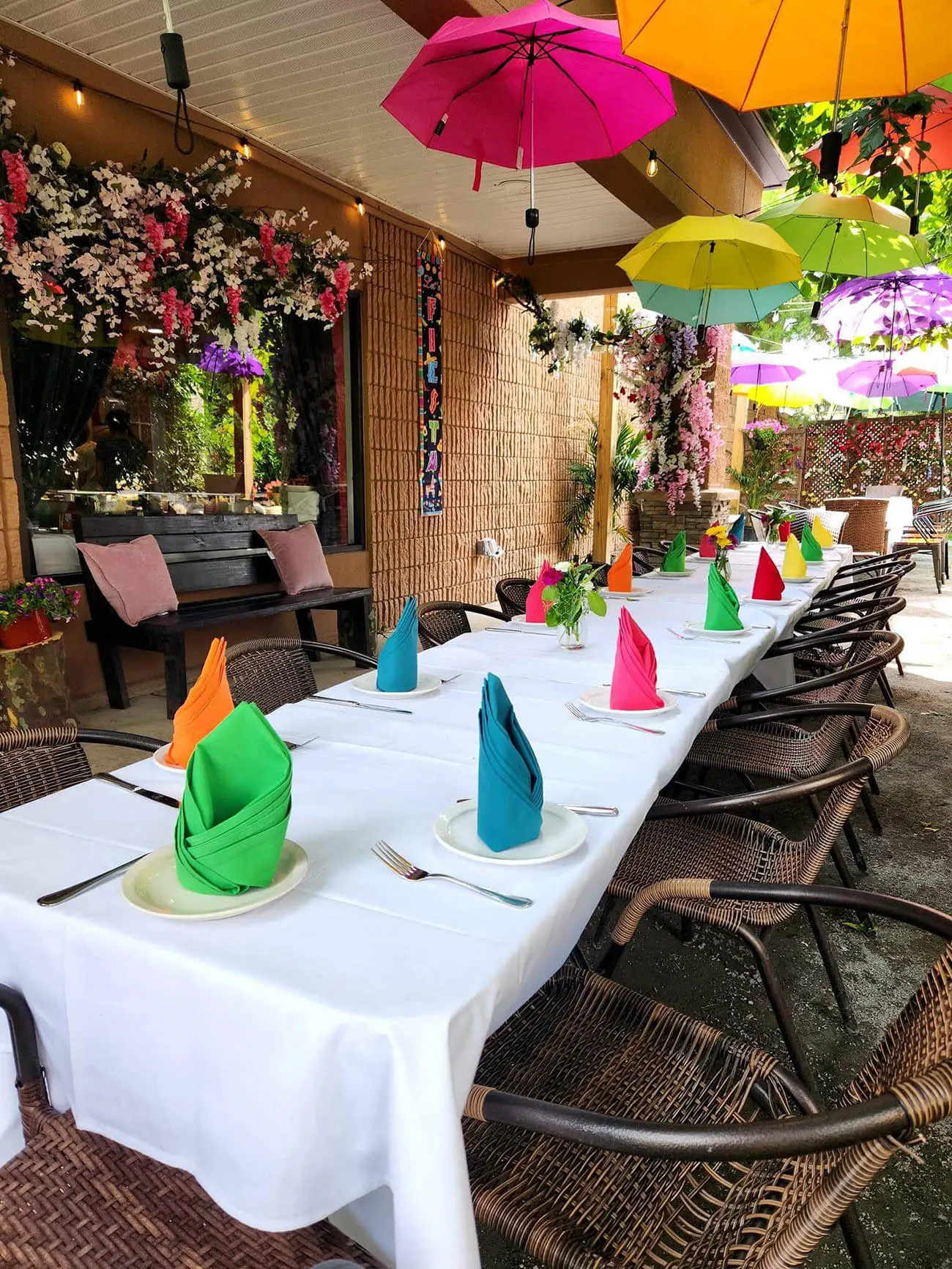 A long table on the patio set with colorful folded napkins for a party
