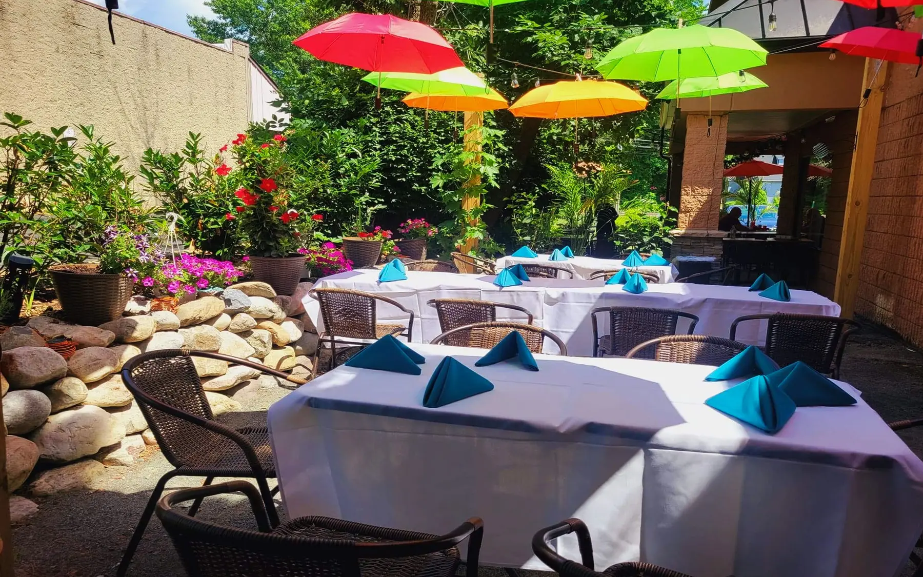 The garden patio at El Mariachi San Lucas: white tables and teal napkins under pink, green and yellow umbrellas