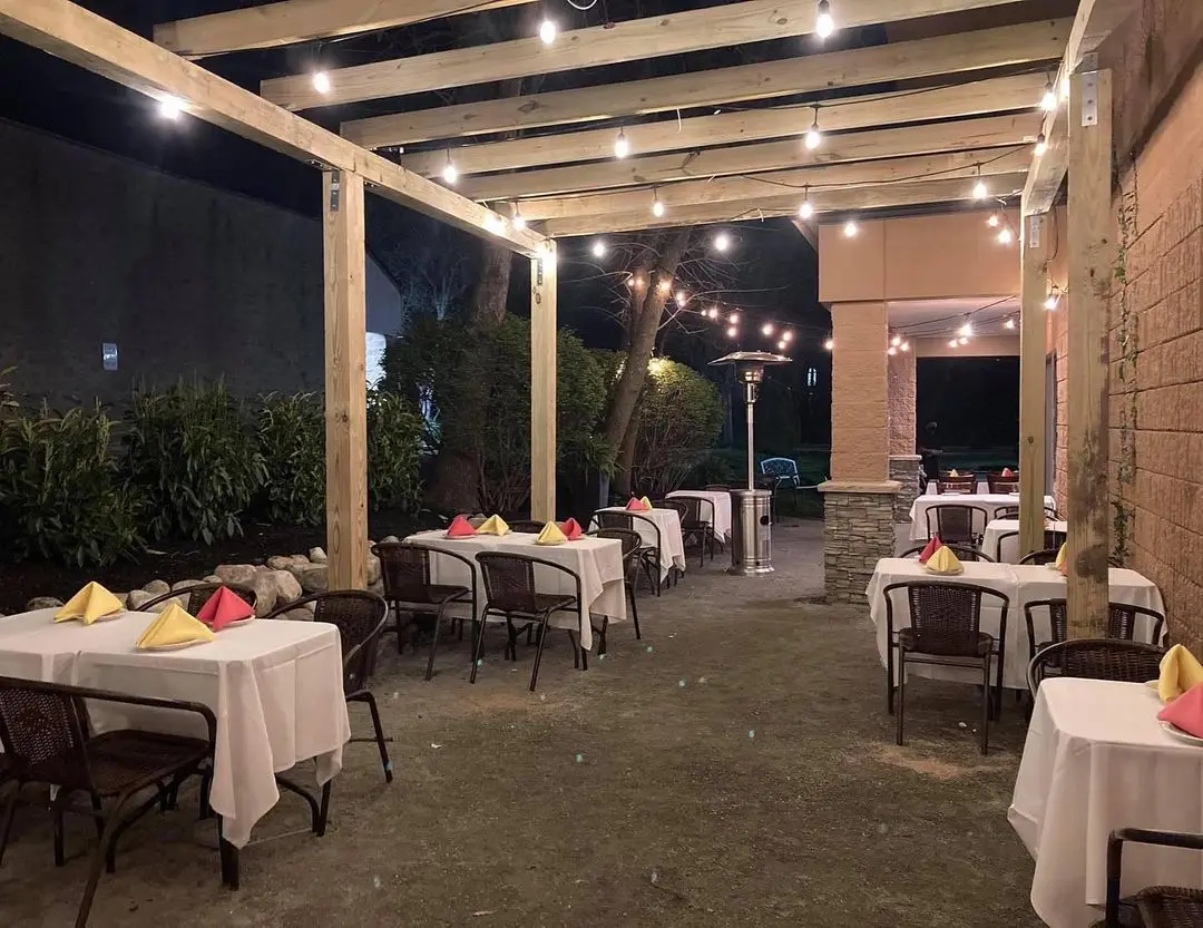 The pergola at night, strung with lights over tables set for dinner