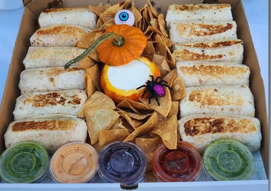 Twelve mini burritos around a pumpkin of queso, with chips and five salsas
