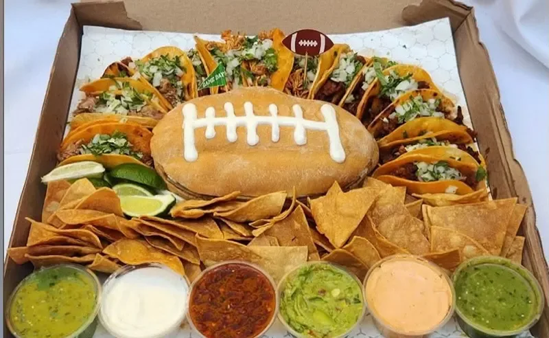 Tacos ringed around a football-shaped torta, with chips, guacamole and salsas