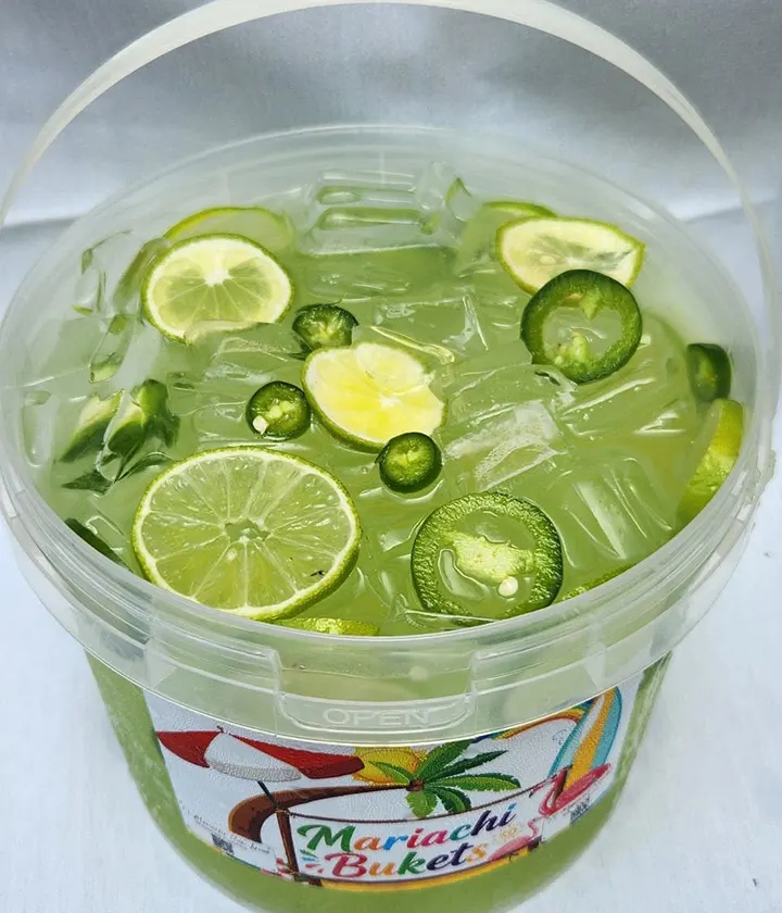 A bucket of iced lime drink with lime wheels and sliced jalapeño