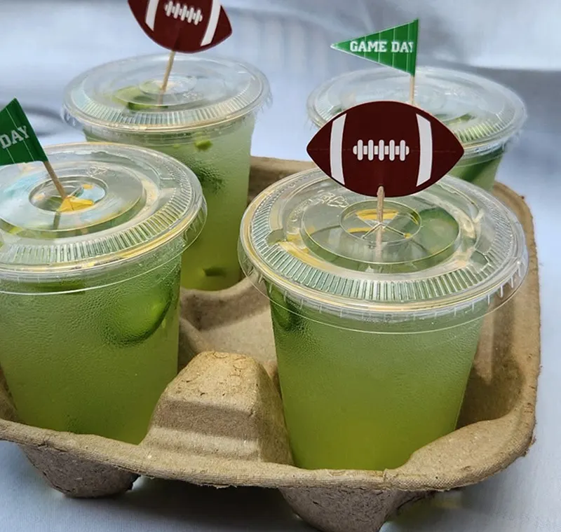 Four lime drinks in a carrier, topped with paper footballs and game-day flags