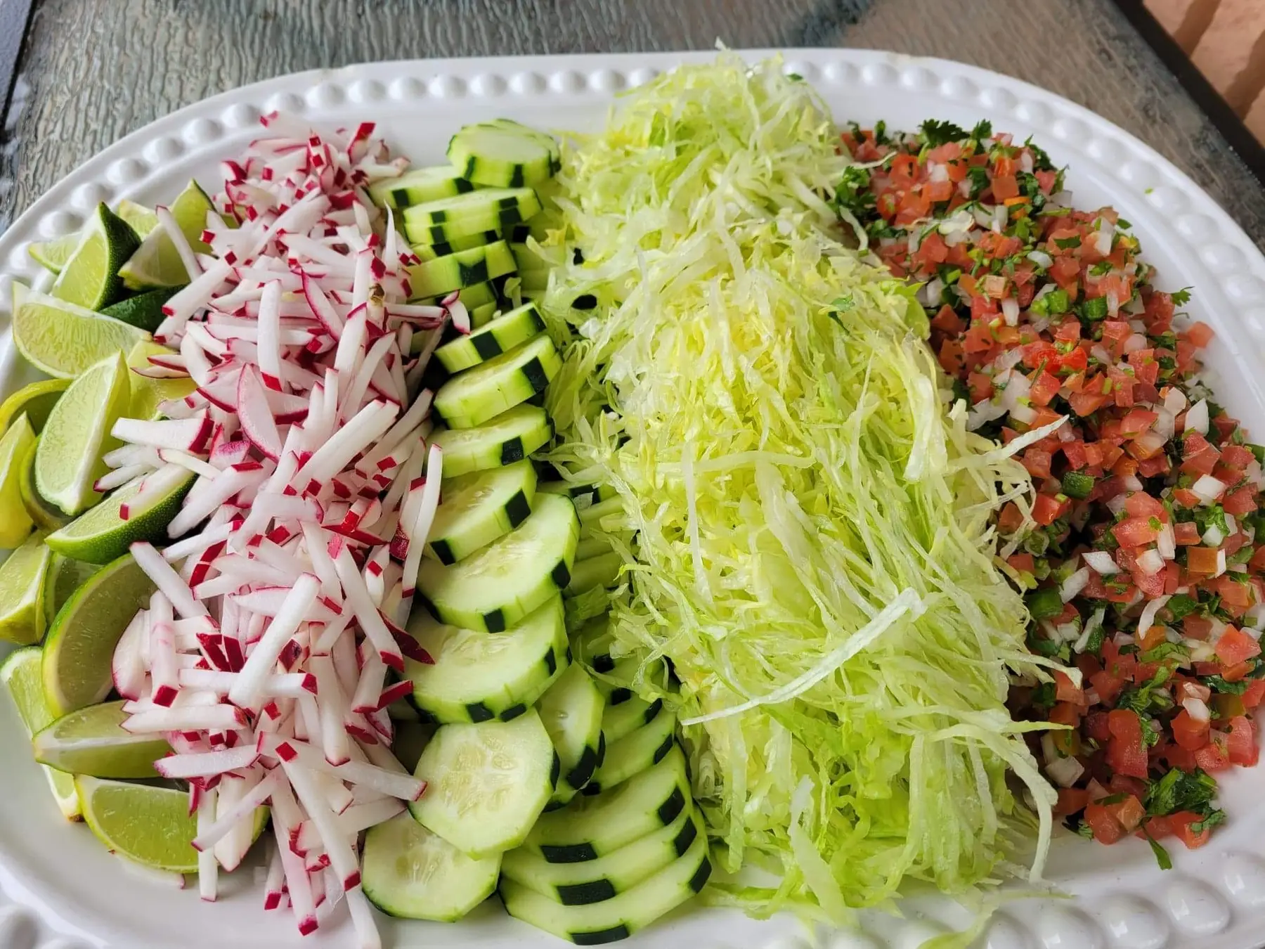 Taco bar toppings: radish, cucumber, cabbage, pico de gallo and limes